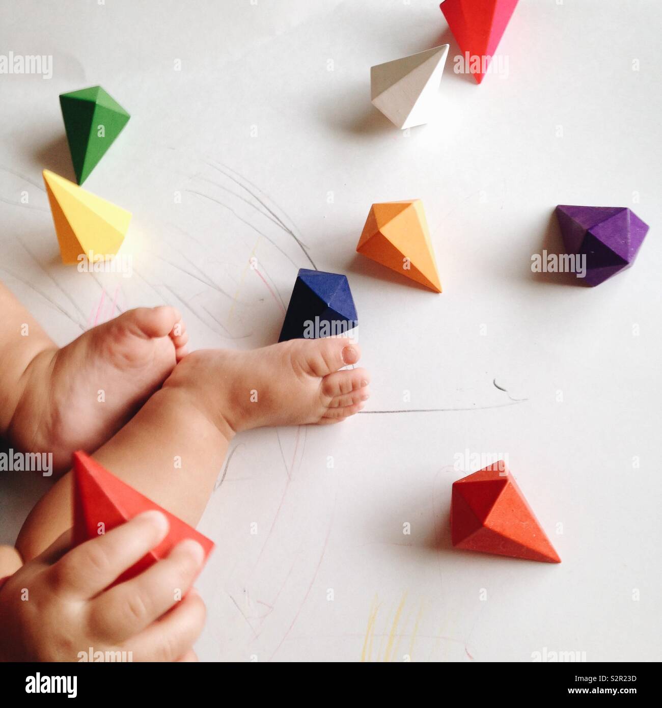 Pieds bébé entouré de diamants colorés sur fond blanc. Banque D'Images
