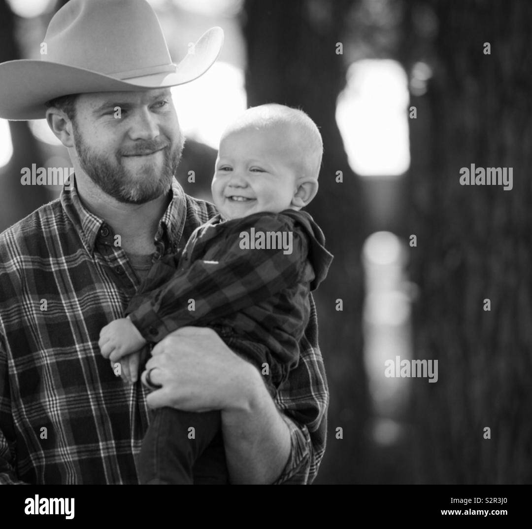 Fier père portant un chapeau de cowboy en tenant son plus jeune fils - Image de stock capturée avec un smartphone