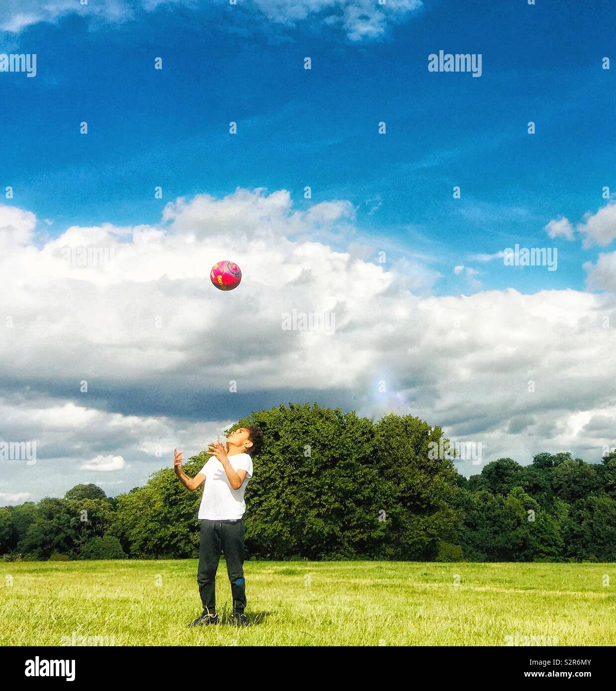 Un enfant, à lancer une boule rouge dans l'air. - Image de stock capturée avec un smartphone