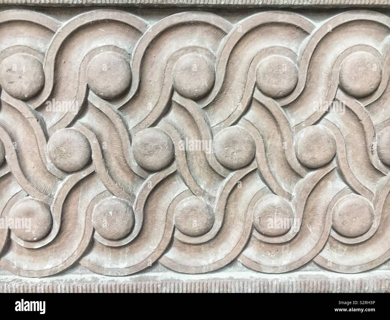 Des détails architecturaux en béton des parchemins et des cercles dans un motif répétitif. - Image de stock capturée avec un smartphone