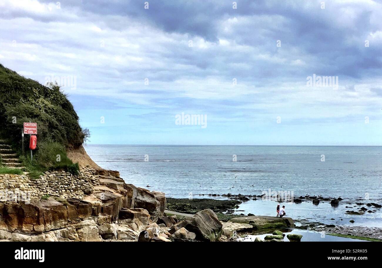 Père et fille l'étude par des rochers à une station paisible située à Scalby Mills, près de Scarborough, North Yorkshire, UK. Cet endroit est près de Scalby Ness les rochers et la plage de North Bay. Banque D'Images