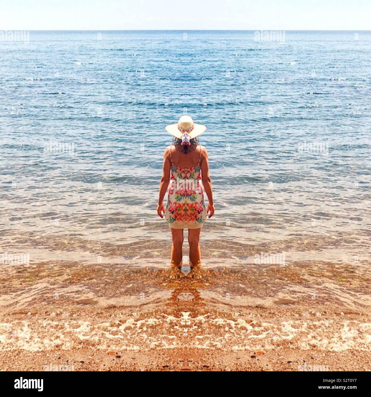 Femme debout dans les eaux peu profondes à la mer Banque D'Images