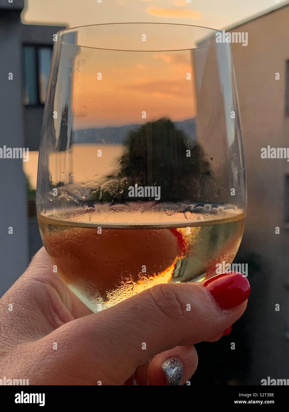 Vue sur la mer au coucher du soleil à travers un verre de vin blanc. Trieste, Italie. Banque D'Images