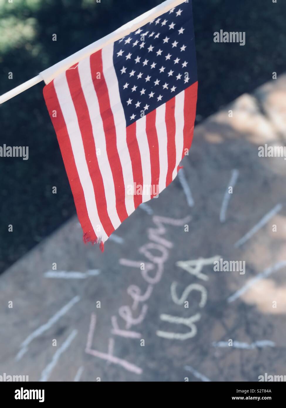 La tenue d'un drapeau américain sur les mots liberté USA écrit en craies de trottoir sur la chaussée à l'extérieur sur un après-midi d'été. USA, l'Amérique Banque D'Images