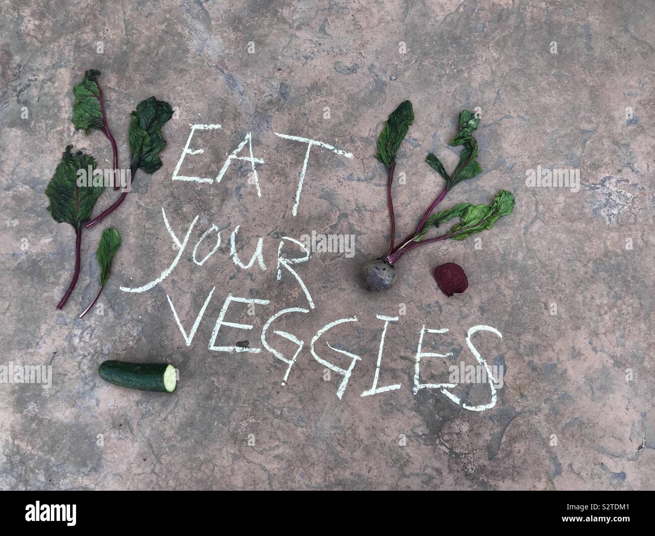 Mangez vos légumes écrit avec craies de trottoir à l'extérieur entouré de betteraves et concombres Banque D'Images