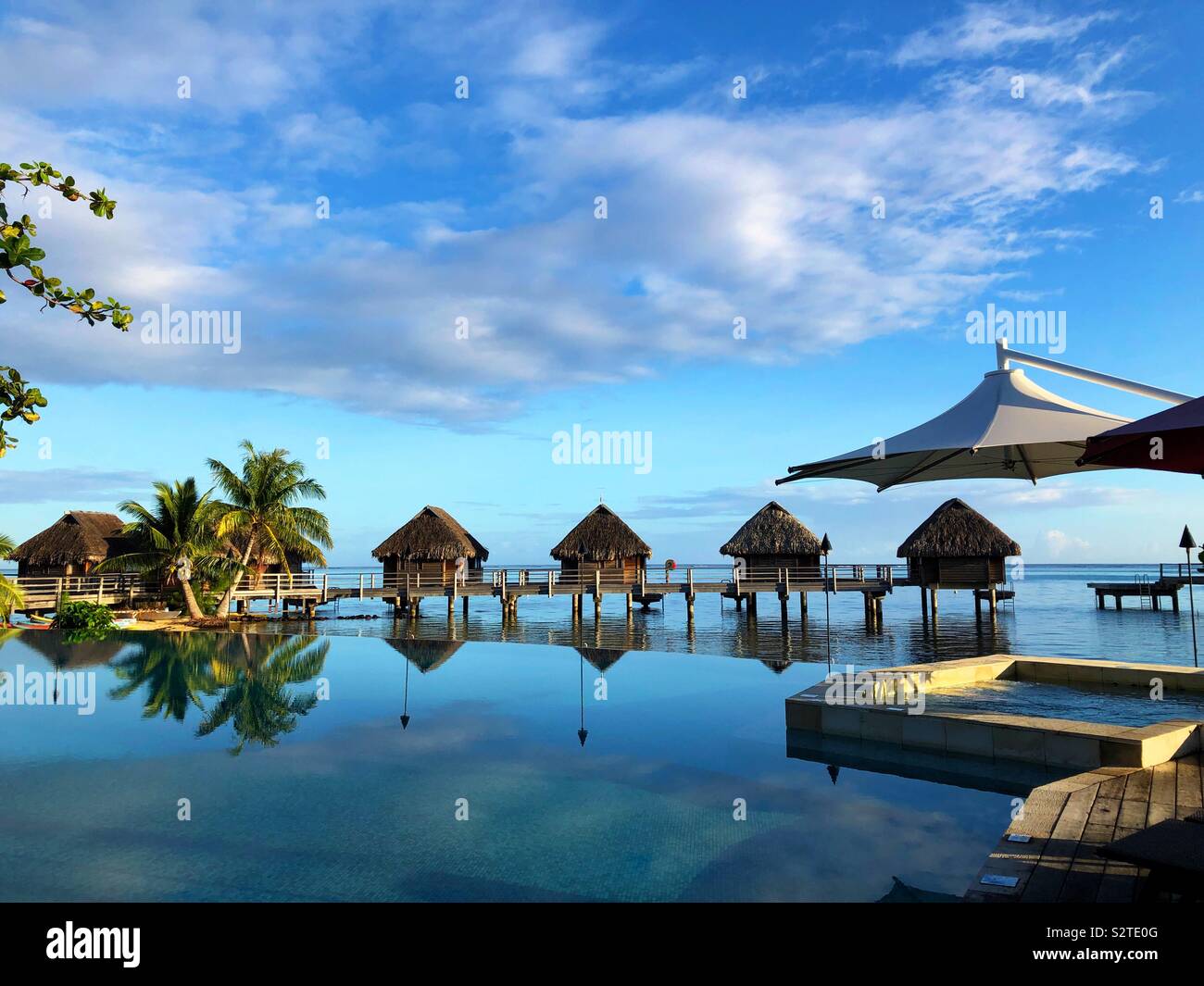 Piscine à débordement, spa, et bungalows sur pilotis dans un hôtel à Moorea, Polynésie Française Banque D'Images