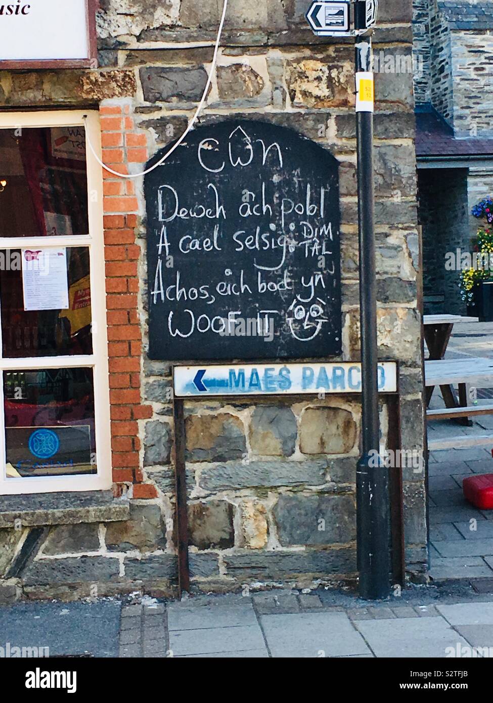 Signe de la langue galloise : 'Dogs, apportez votre homme. Get a free sausage - parce que vous êtes woof !' sur un café à Cardigan, Wales. Banque D'Images