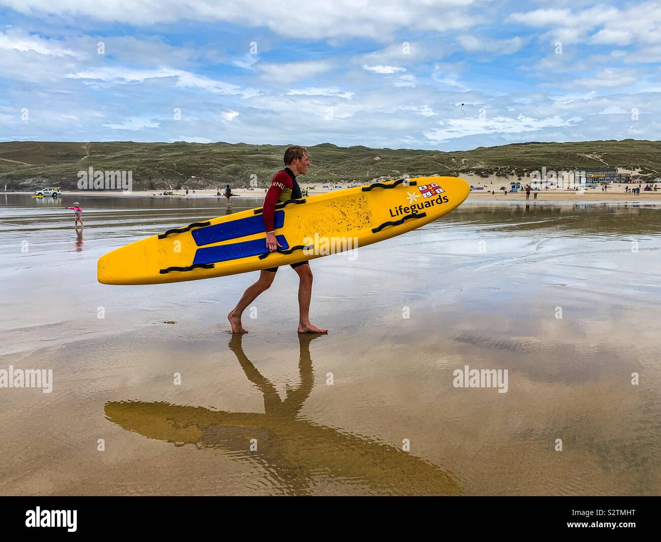 Sauveteur RNLI marchant sur la plage de perran jaune transport surf board à Cornwall - Image de stock capturée avec un smartphone