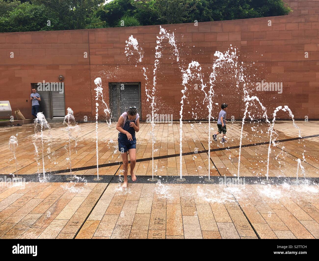 Enfants jouant dans les fontaines d'eau sur une chaude journée d'été. Banque D'Images