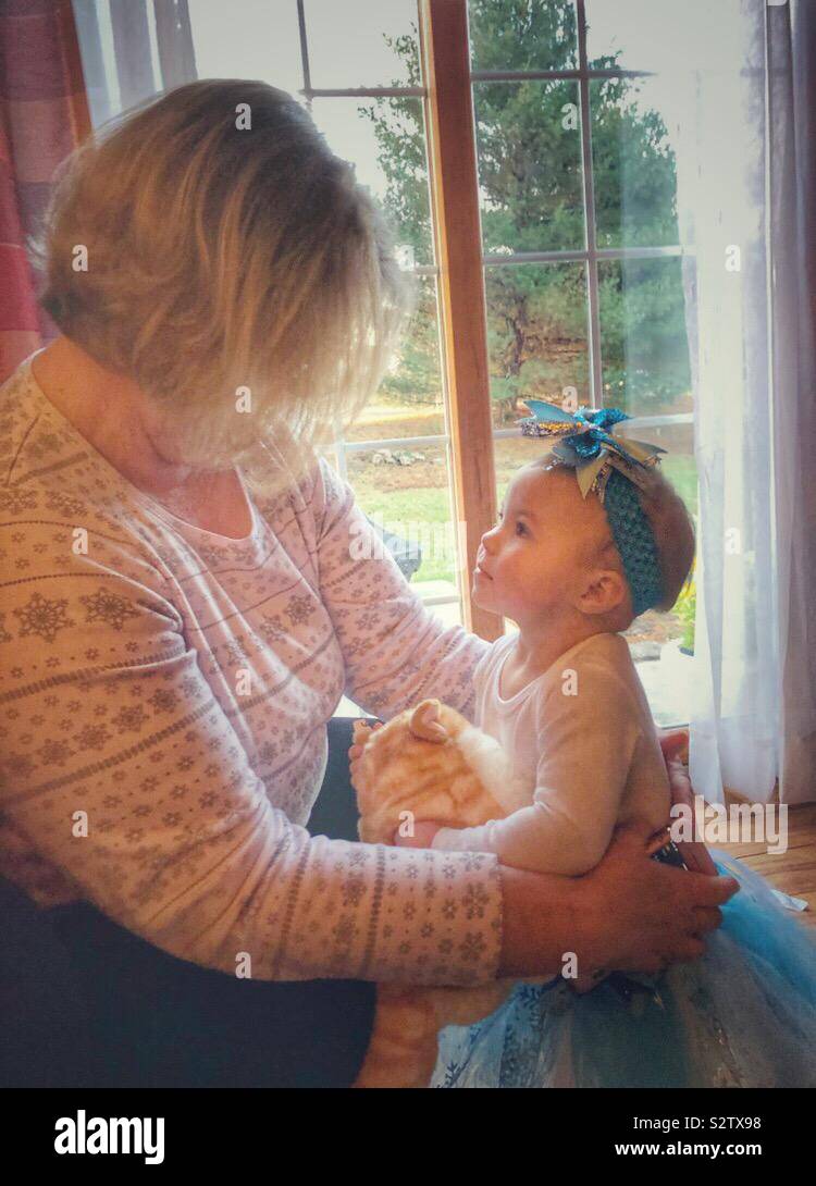 Un bébé fille en regardant le visage de sa grand-mère. Banque D'Images