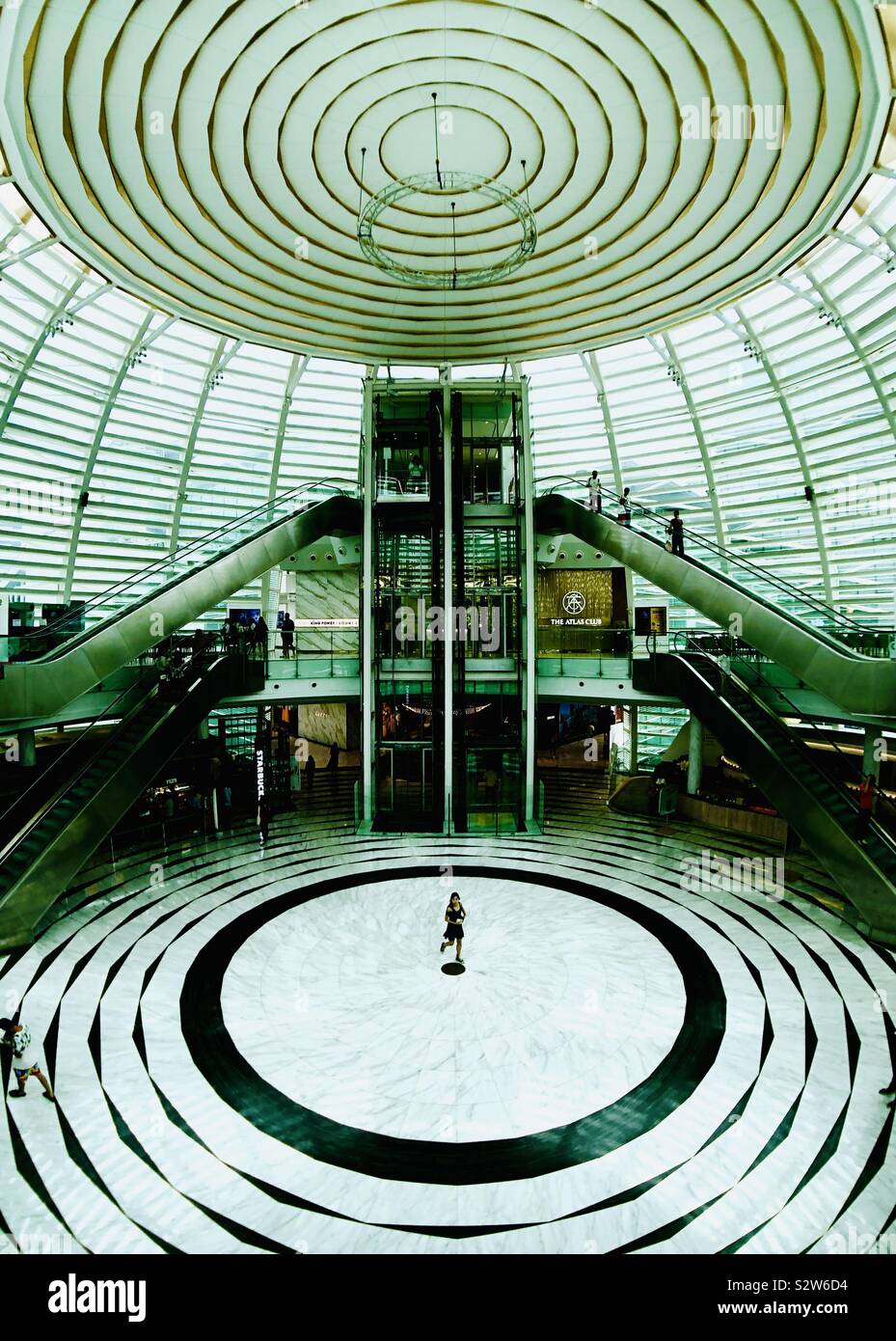 Dôme en verre circulaire atrium lignes symétriques. Une femme seule traverse le centre point. La conception architecturale de la symétrie. Banque D'Images