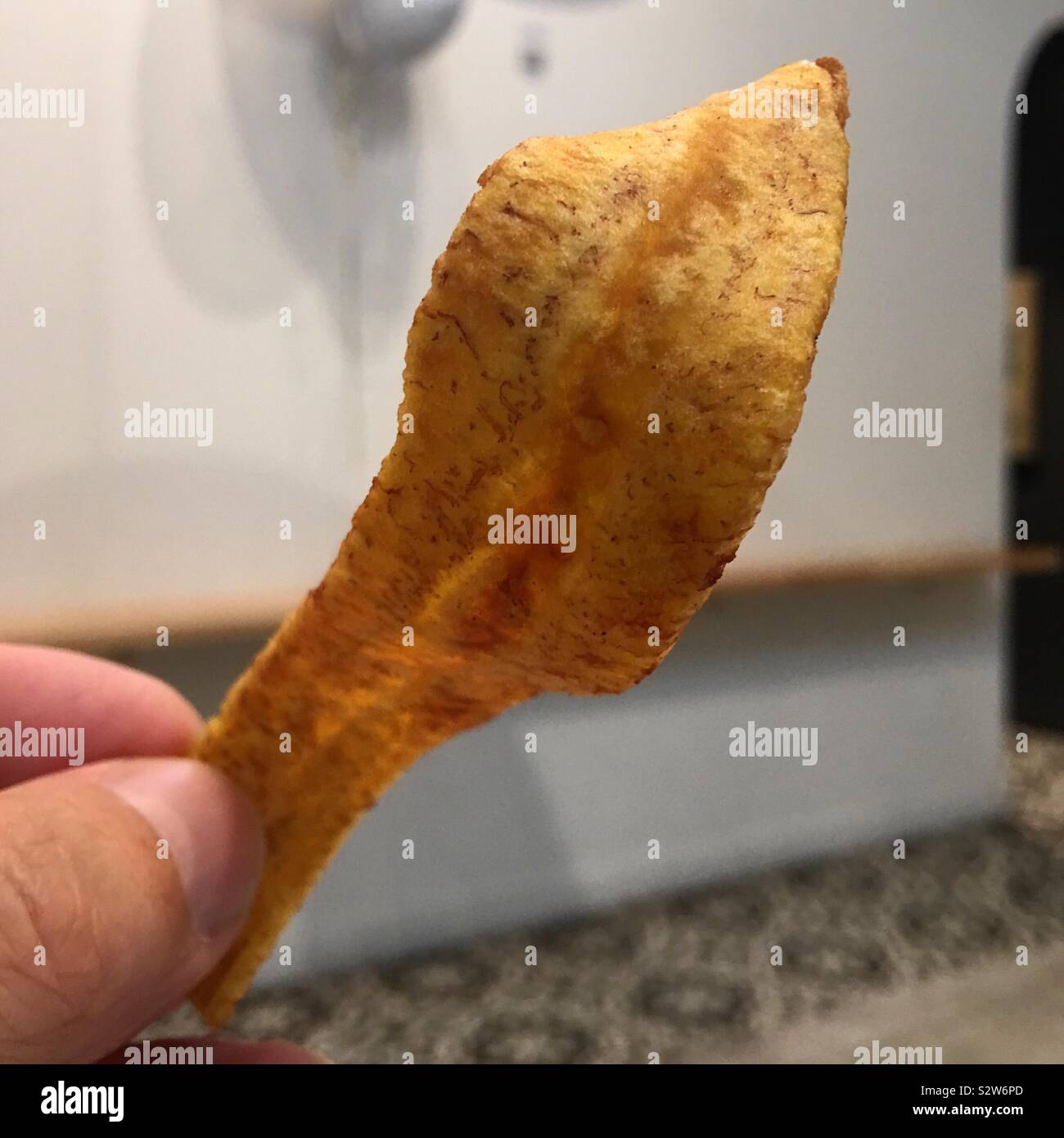 Coupe frites de bananes plantain tenu par le pouce et l'accent peu profondes, Banque D'Images