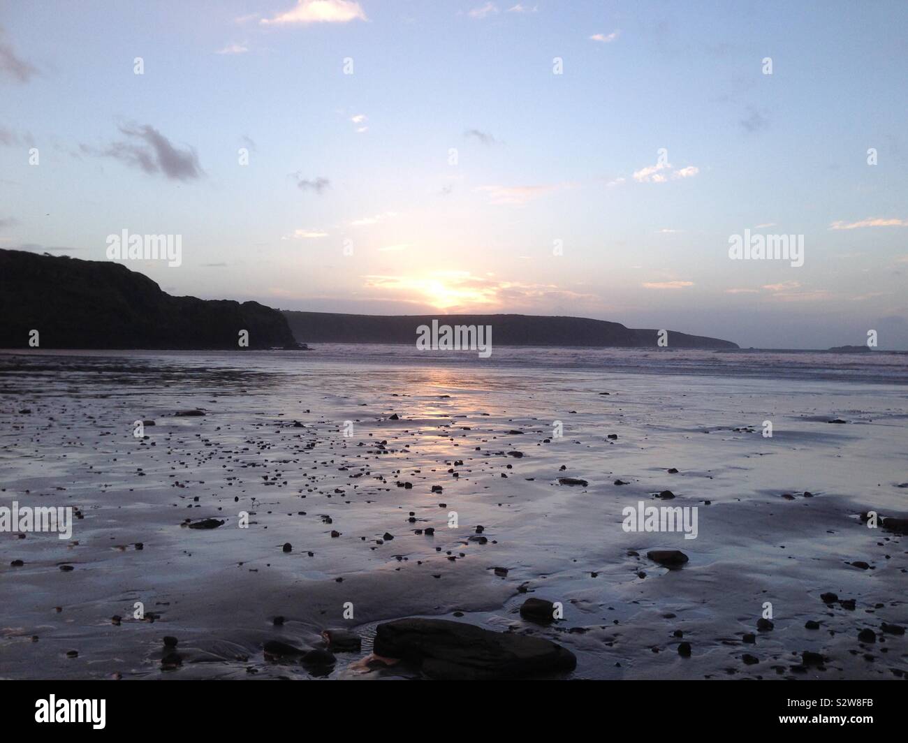 Coucher du soleil qui se reflète sur le sable sur une plage de Pembrokeshire. Pays de Galles, Royaume-Uni Banque D'Images
