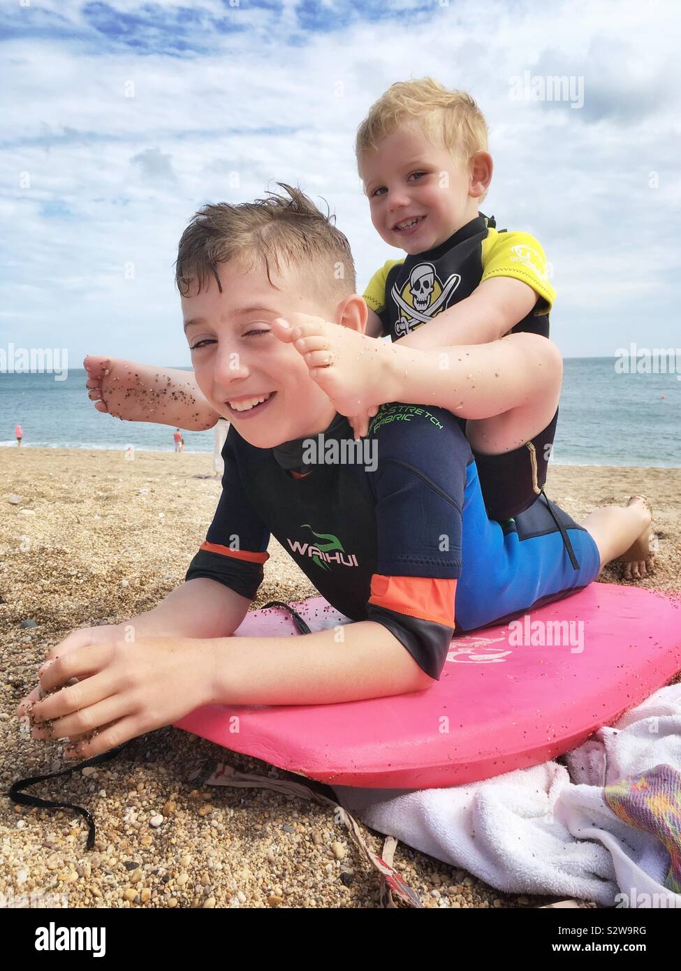 Deux frères en combinaisons à Blackpool Sands Beach, Dartmouth, Devon, Angleterre, Royaume-Uni. Banque D'Images