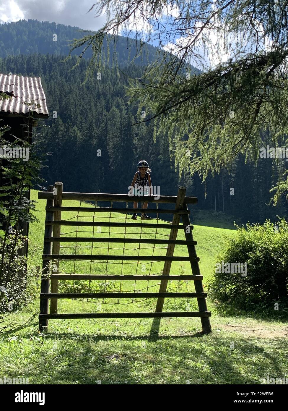 Petite fille avec casque de vélo escalade dans un jeux dans les montagnes. Sesto, Italie. Banque D'Images