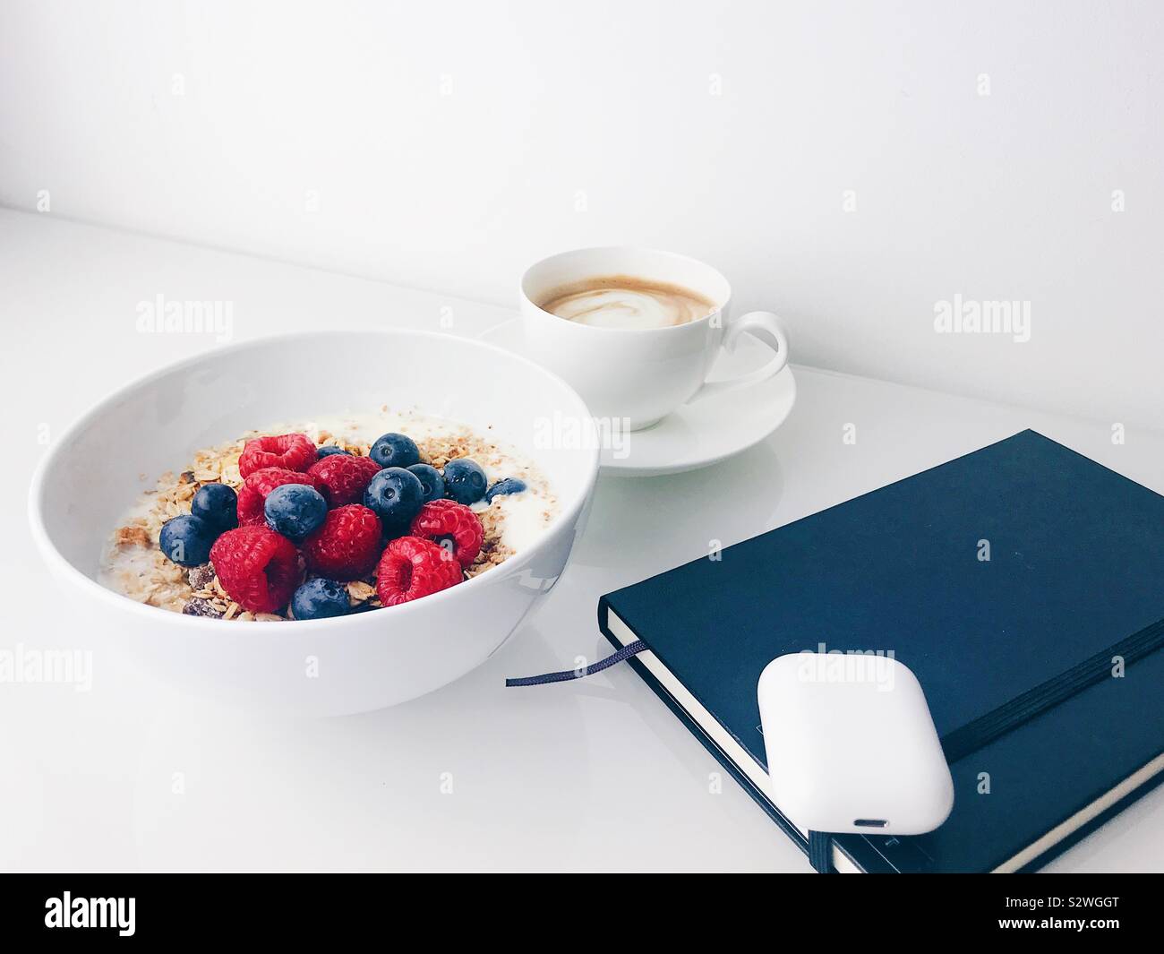 Céréales Petit-déjeuner sain avec des framboises, des bleuets, du café avec un ordinateur portable et un casque Banque D'Images