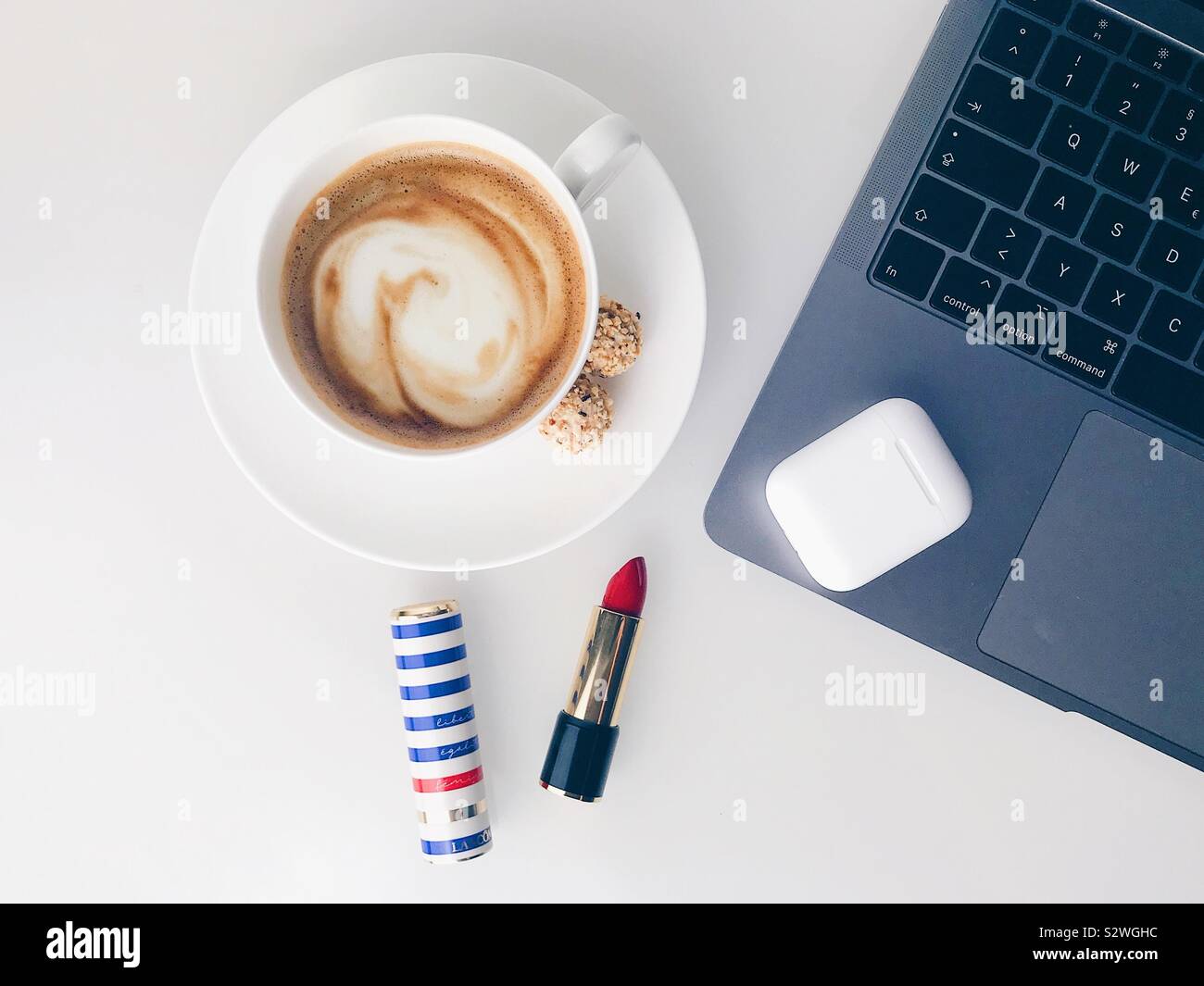 Pause café cappuccino avec le rouge à lèvres rouge, ordinateur portable et écouteurs Banque D'Images
