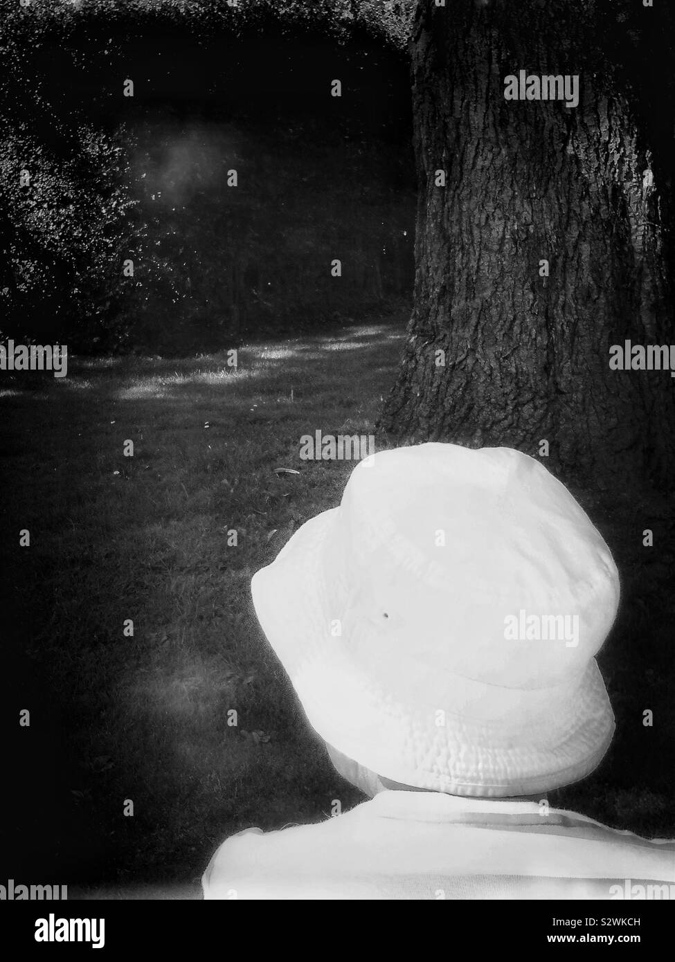 Rear view of woman in white summer hat se détendre dans les jardins en été Banque D'Images