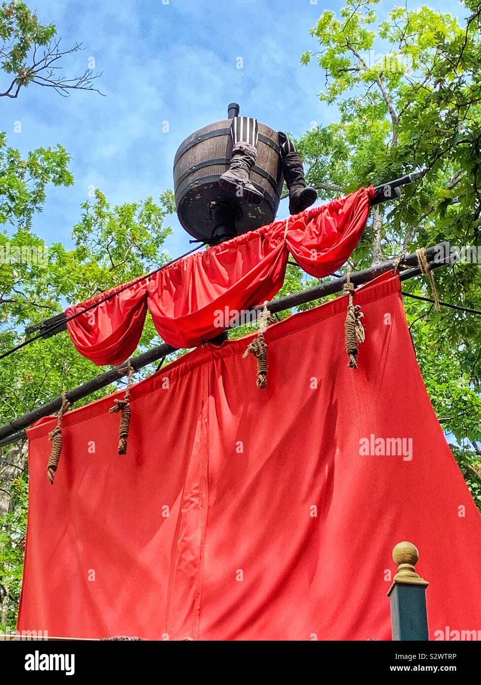 La voile rouge vif et du mât d'un bateau de pirate avec jambes traînant du haut de la benne. - Image de stock capturée avec un smartphone