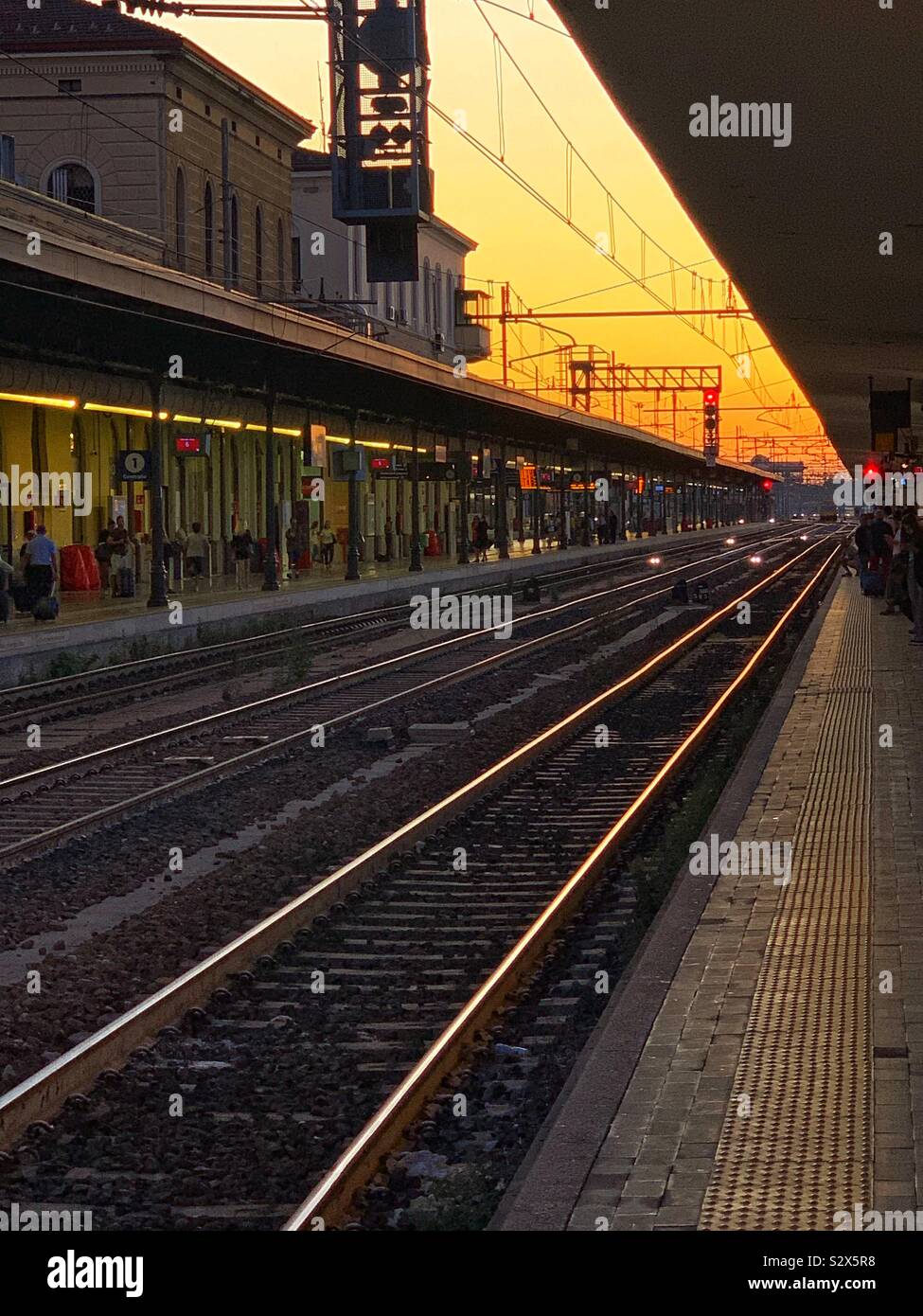 Coucher du soleil sur les rails à la gare centrale de Bologne. L'Italie. Banque D'Images