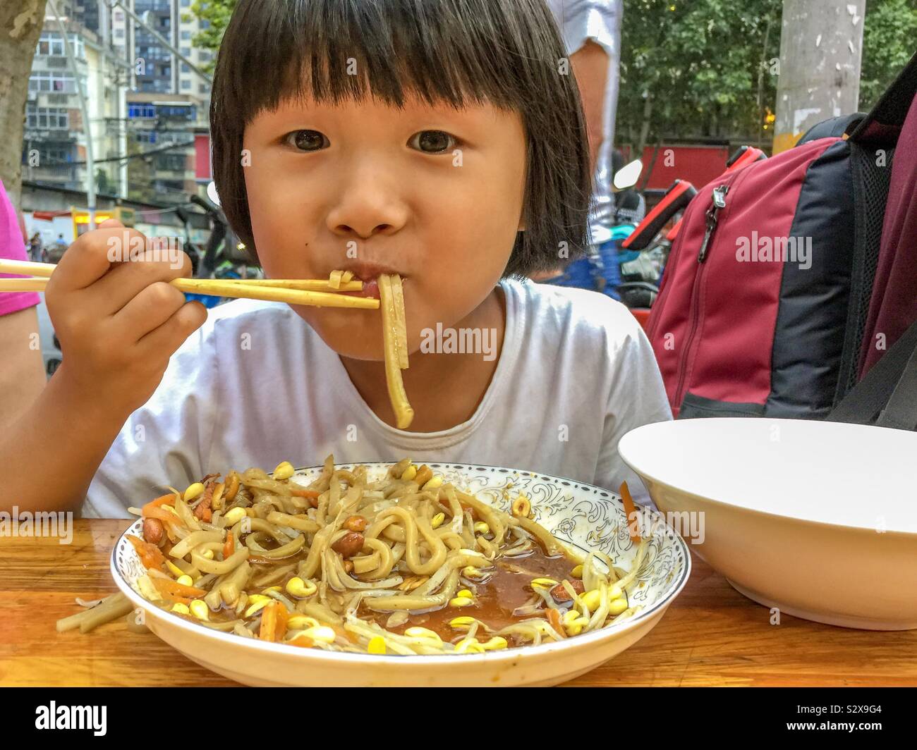 Jeune fille chinoise de manger un bol de nouilles Banque D'Images