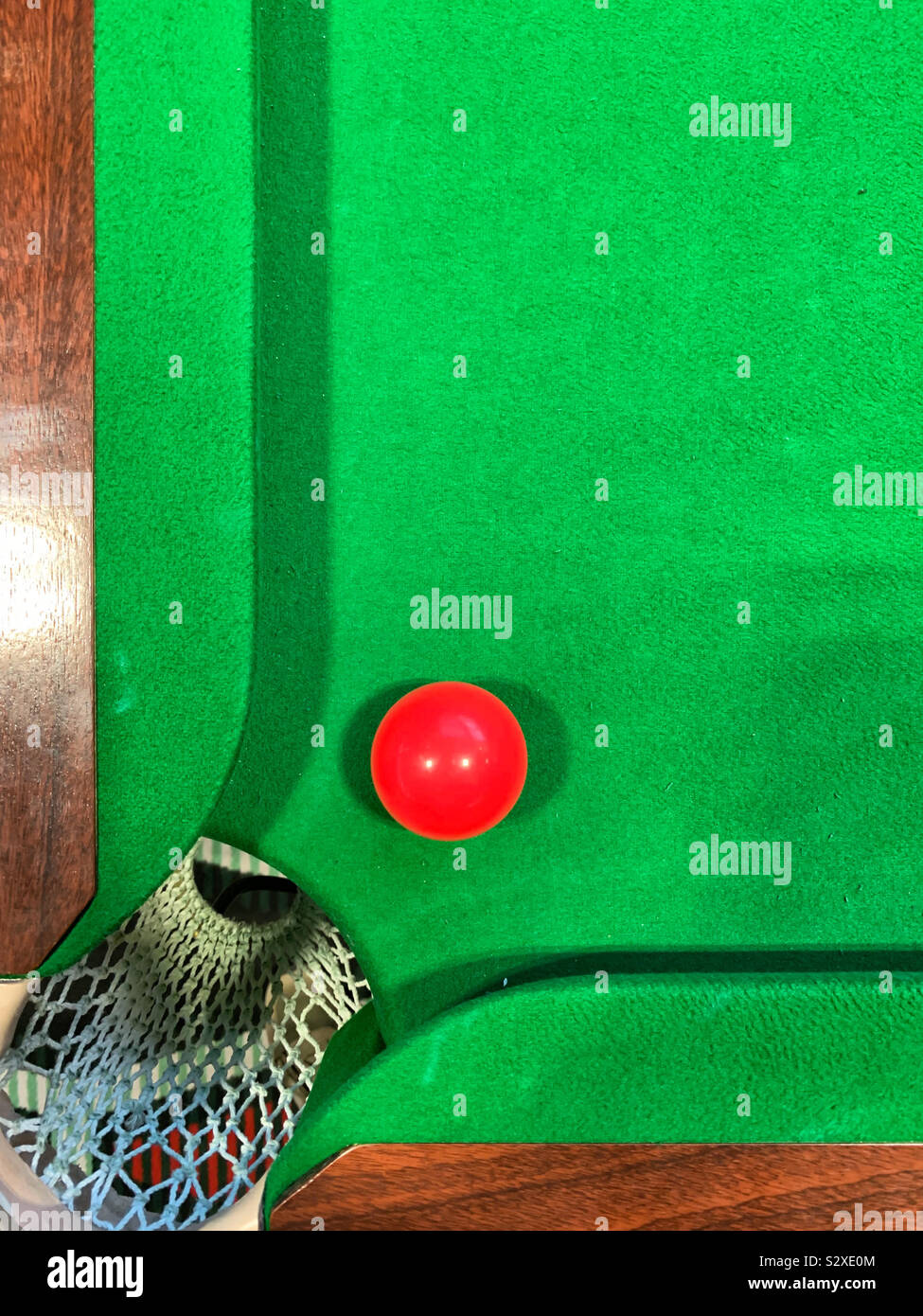 Boule de billard rouge près d'une poche sur une table de billard vert Banque D'Images