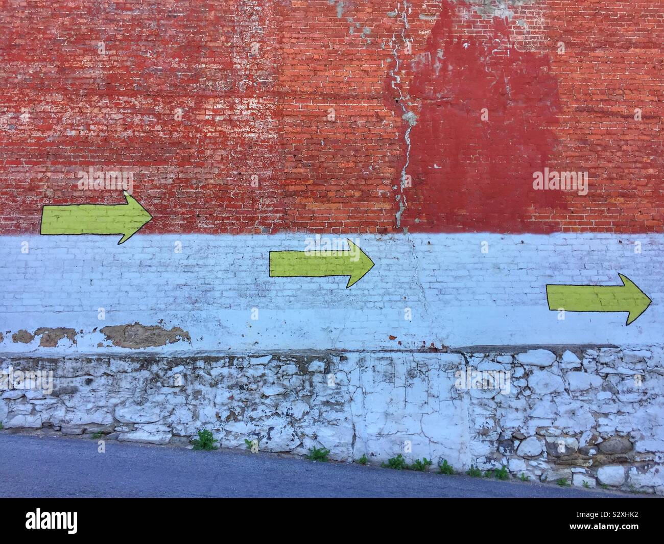 Flèches jaunes peintes sur un vieux mur de brique - Image de stock capturée avec un smartphone