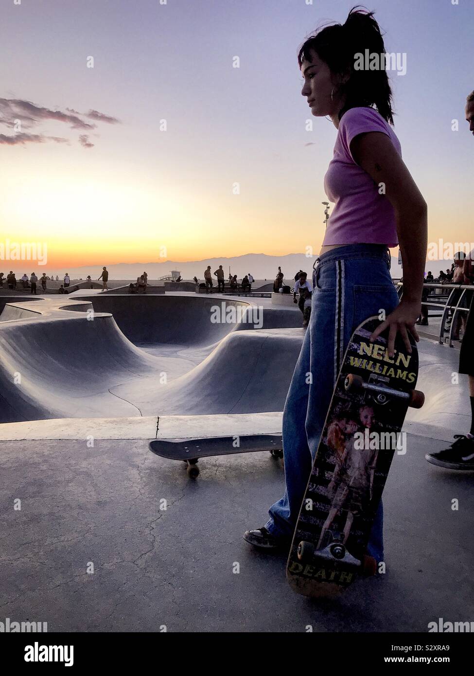 Skate girl en contemplant les courbes pendant l'heure d'or à Venise CA. Banque D'Images