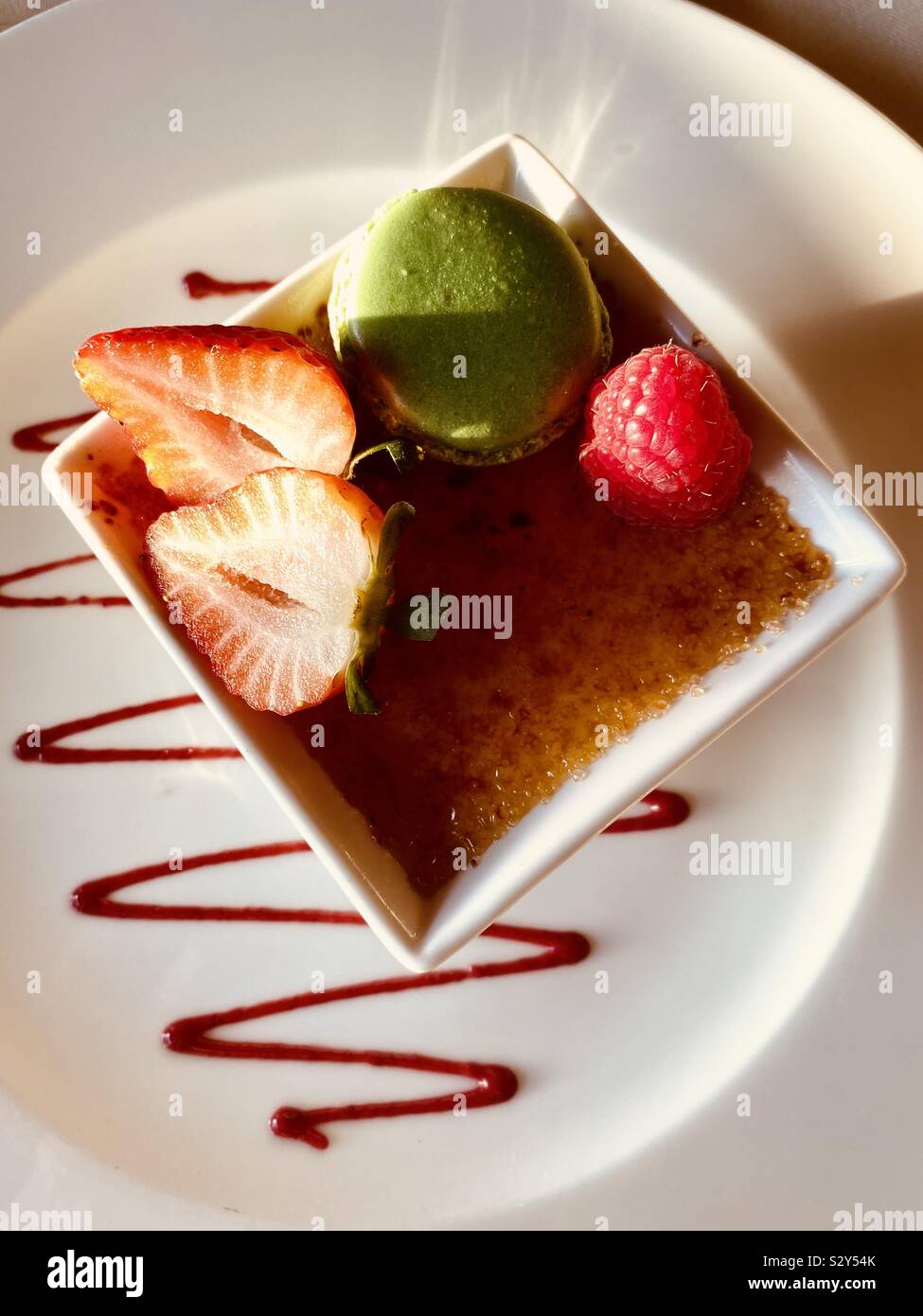 Crème brûlée dessert avec des fraises, framboises et biscuit sur une plaque blanche décorative Banque D'Images