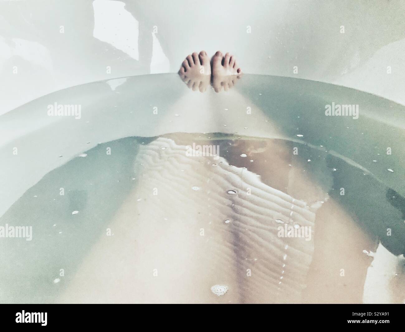 Les jambes des femmes dans un bain avec orteils qui sort Banque D'Images