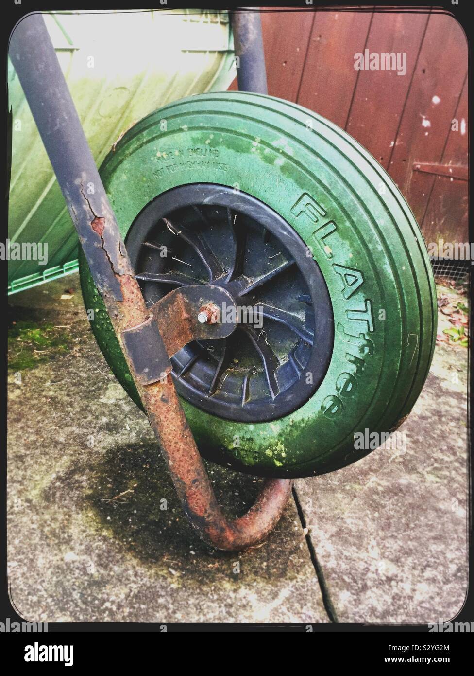 Roue verte d'une brouette retournée sur une pelouse de jardin Banque D'Images