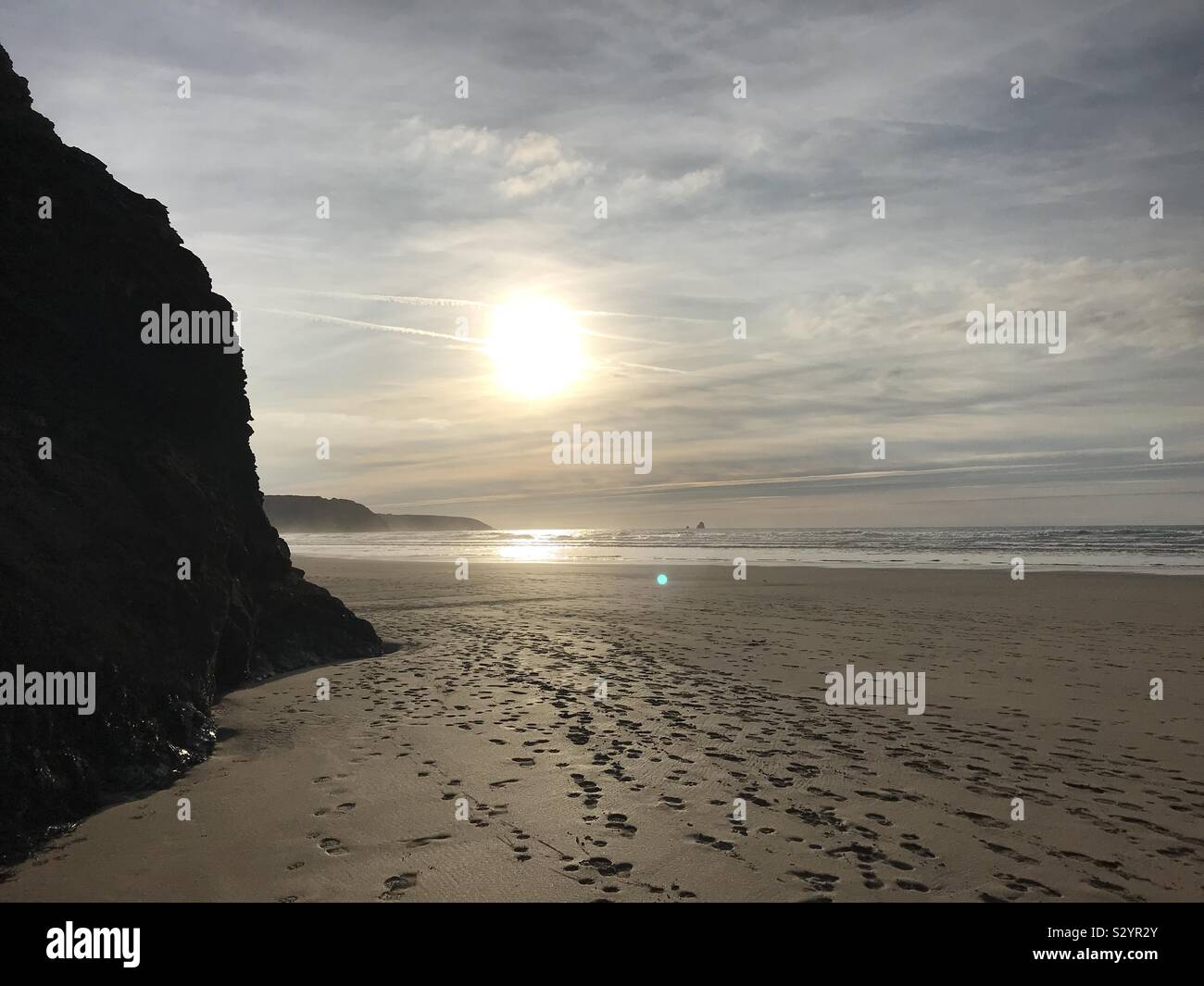 Soleil sur plage avec des silhouettes de falaise Banque D'Images