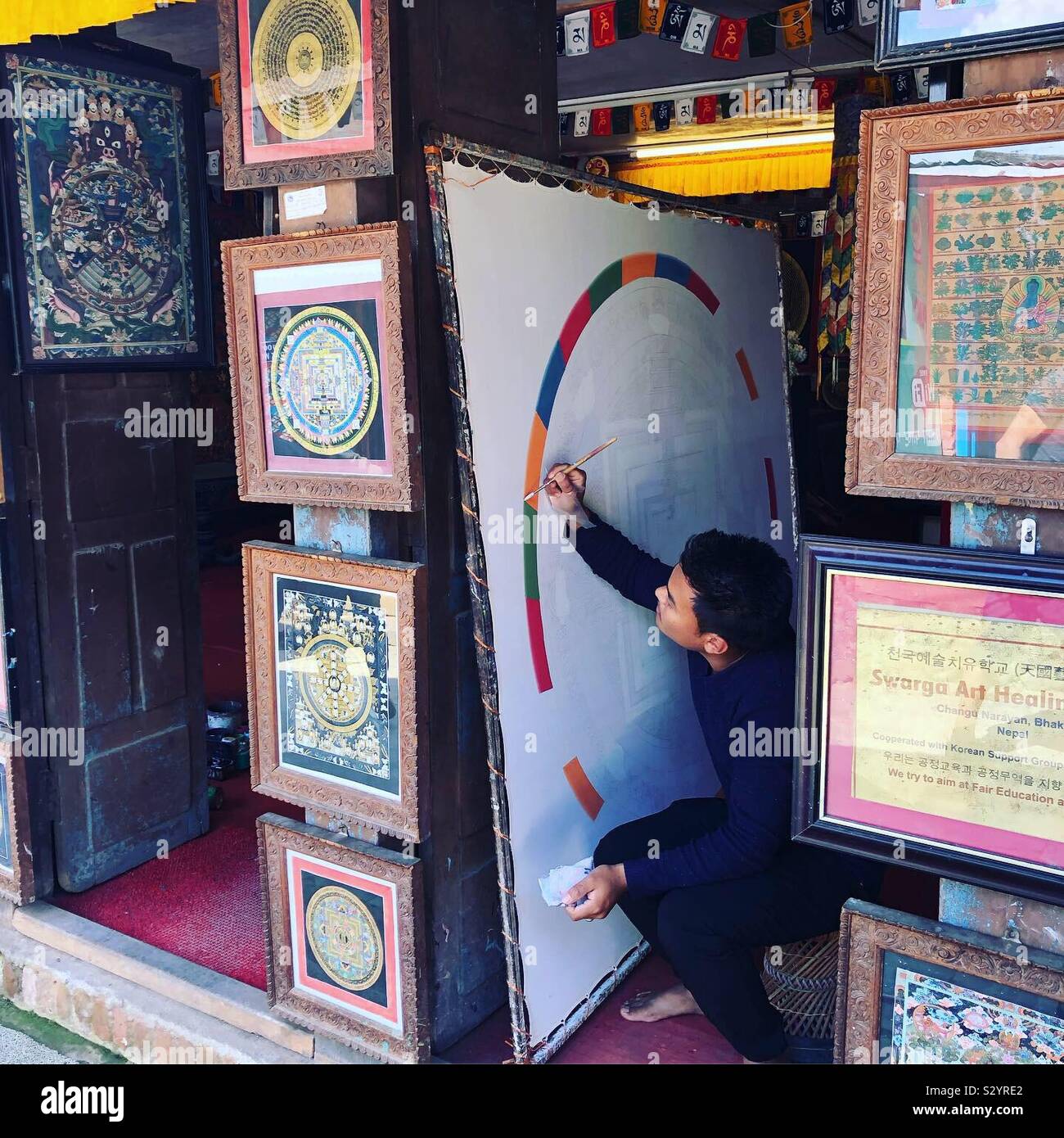 Un jeune artiste en peinture d'un mandala traditionnel dans la vallée de Katmandou, Népal. - Image de stock capturée avec un smartphone