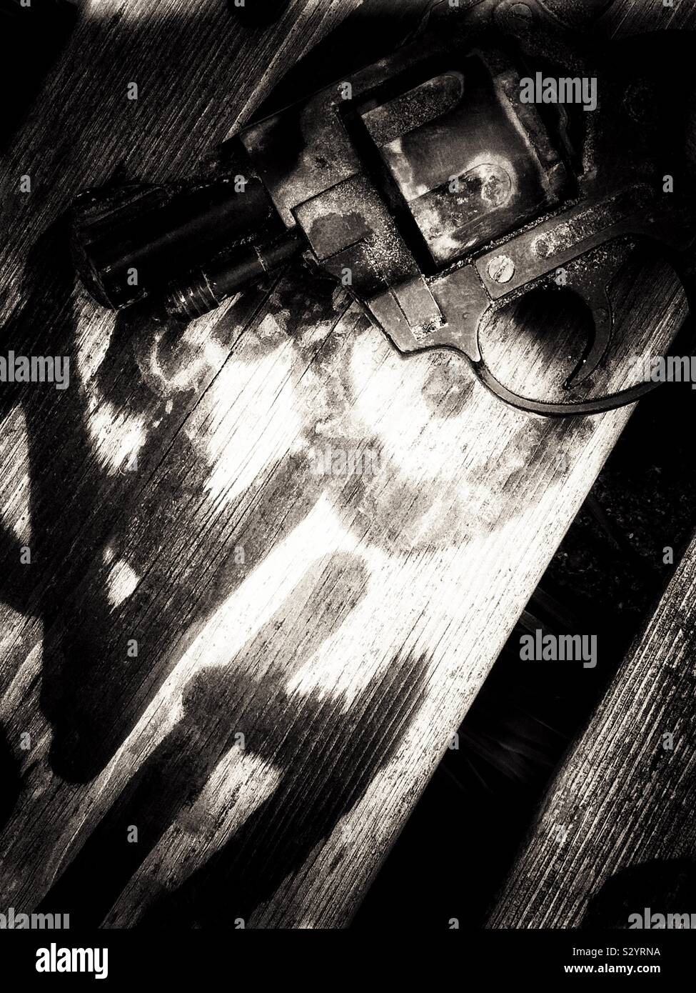 Image en noir et blanc de pistolet revolver poing abandonné sur le siège en bois recouvert de graffitis - Image de stock capturée avec un smartphone