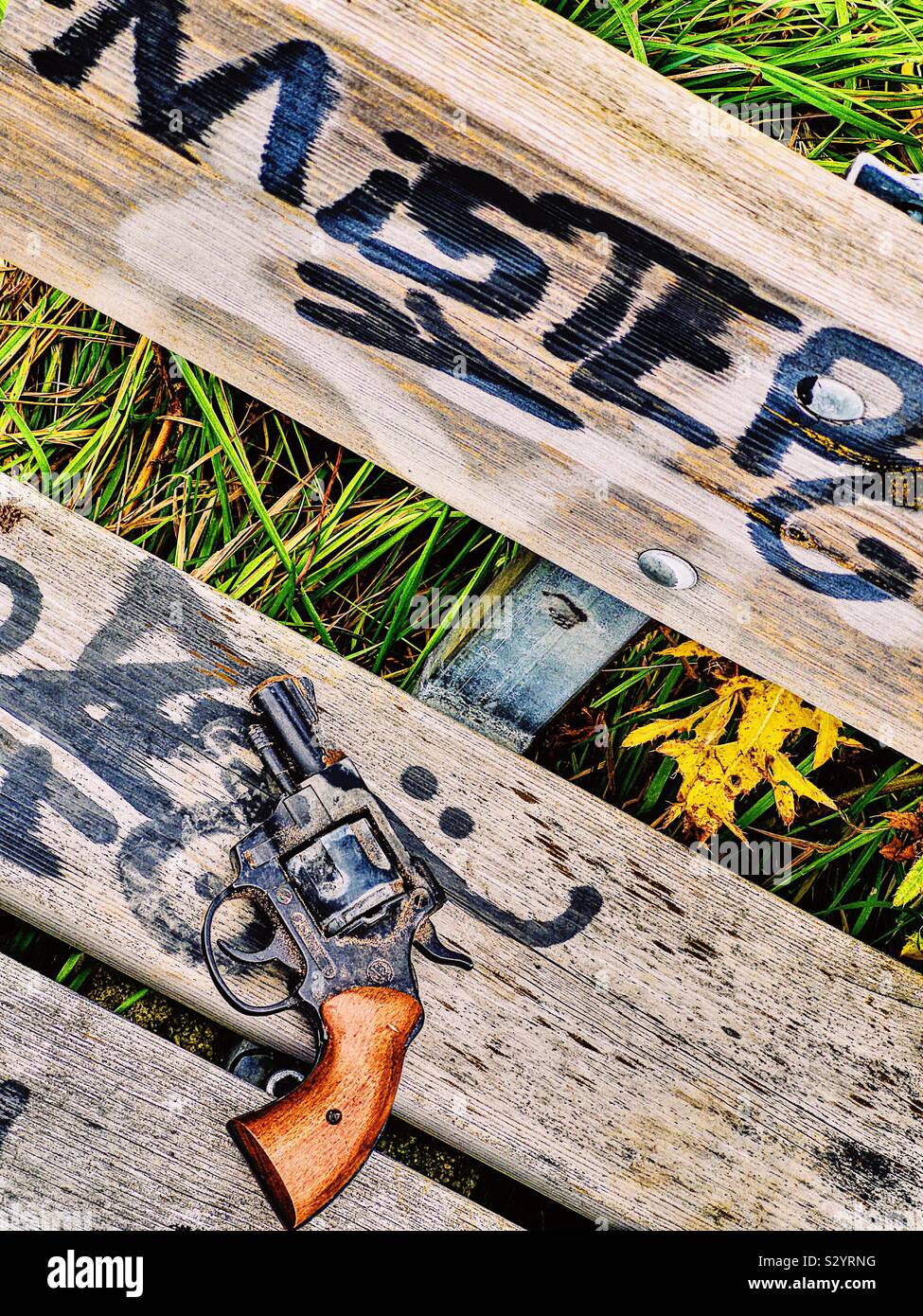 Pistolet pistolet abandonné sur l'assise en bois pulvérisés avec des graffitis et mister word - Image de stock capturée avec un smartphone