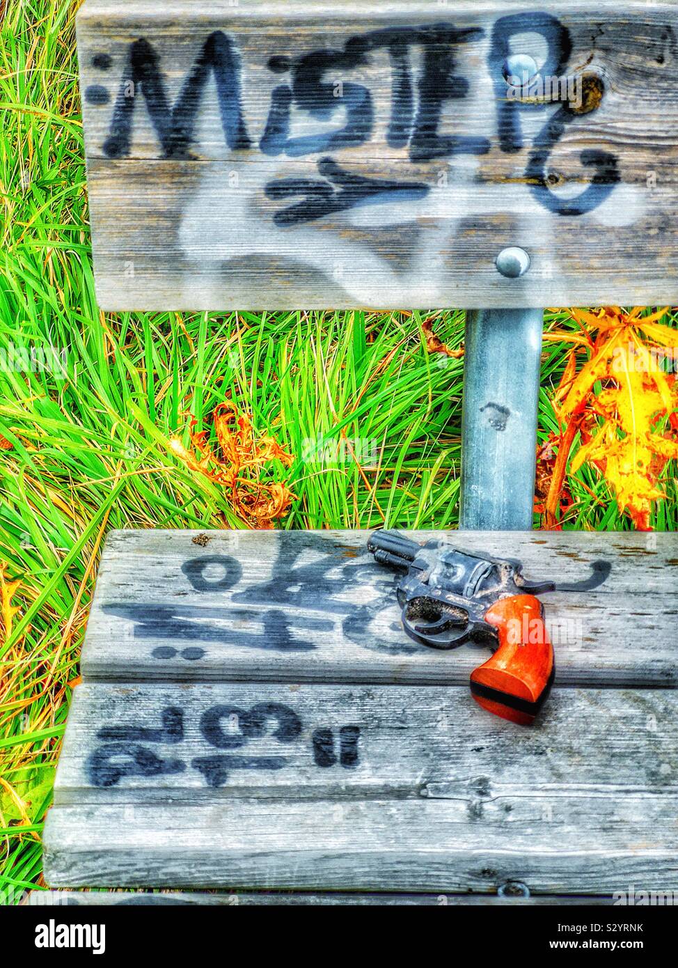 Pistolet pistolet abandonné sur l'assise en bois pulvérisés avec des graffitis et mister word - Image de stock capturée avec un smartphone