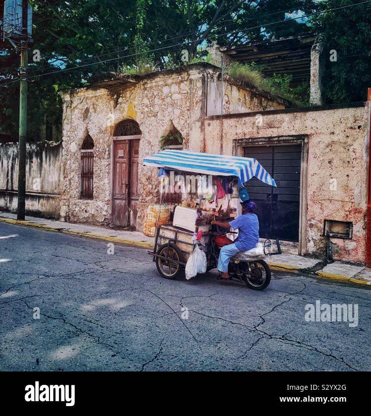 Un homme conduit son chariot motorisé avec les points de vente vers la plaza dans une rue de Mérida, au Mexique. Banque D'Images