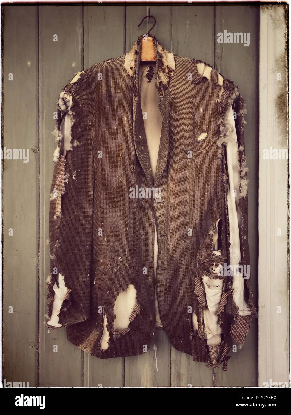 Une vieille veste de se désintégrer sur son cintre comme il a été exposé pendant environ cinquante ans. - Image de stock capturée avec un smartphone