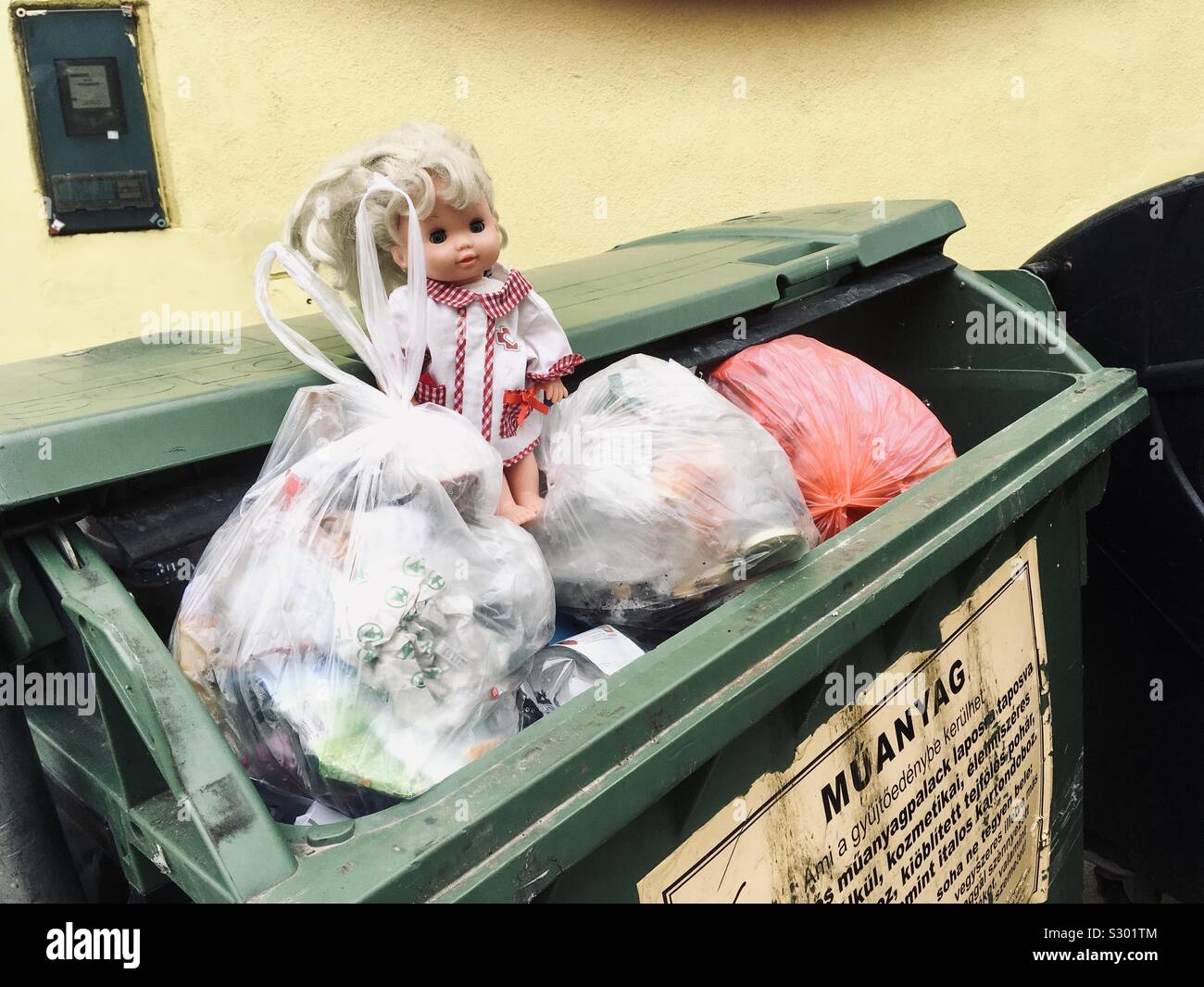 Poupée jouet jeté dans la poubelle de recyclage du plastique dans des sacs de détritus, Sopron, Hongrie - Image de stock capturée avec un smartphone