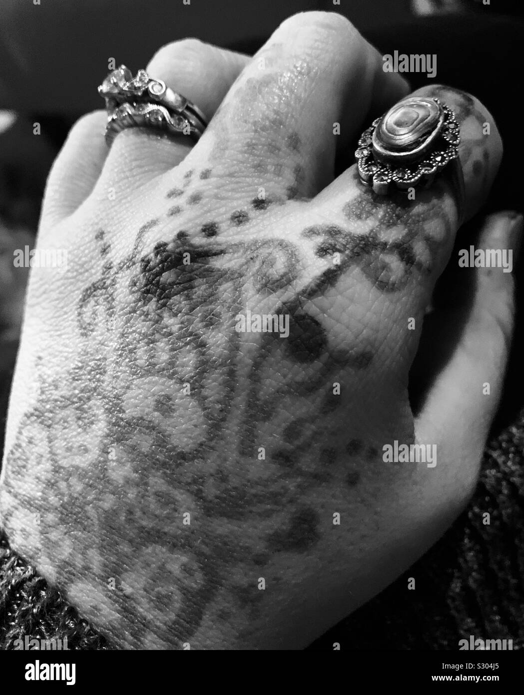 La main avec bagues argent et tatouage au henné Banque D'Images