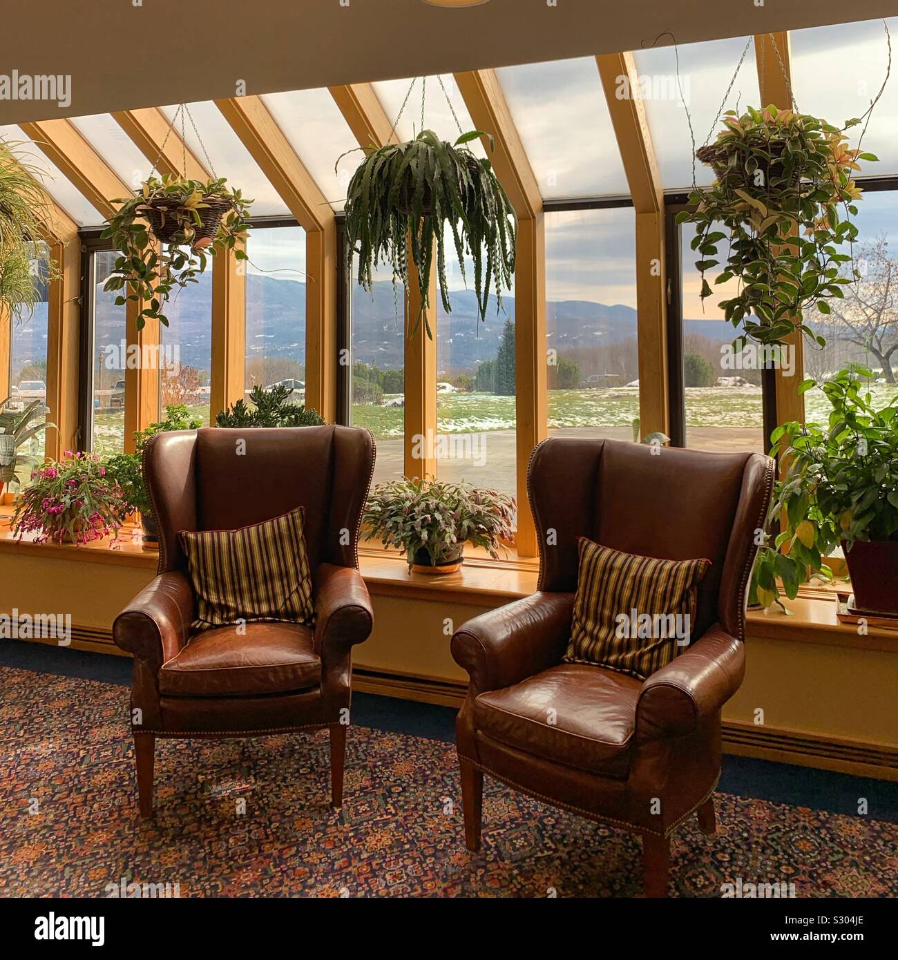 Un salon avec des sièges confortables et des plantes près des fenêtres donnant sur le paysage à la Trapp Family Lodge, Stowe, Vermont, United States Banque D'Images