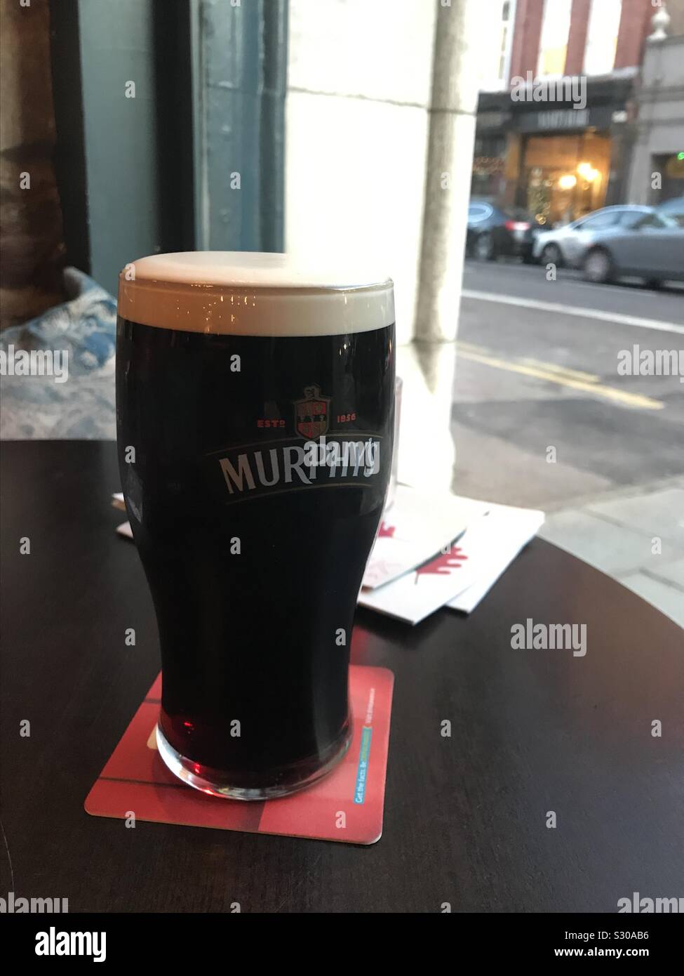 Pinte de bière stout Murphy's sur la table dans la fenêtre de bar Isaacs, Cork Irlande Banque D'Images