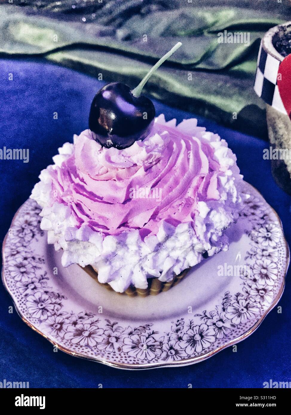 Cupcake sur une soucoupe avec glaçage blanc et rose et d'une cerise sur le dessus. Mad Hatters Tea Party - Alice dans le palais à Noël, Blenheim Palace - Image de stock capturée avec un smartphone