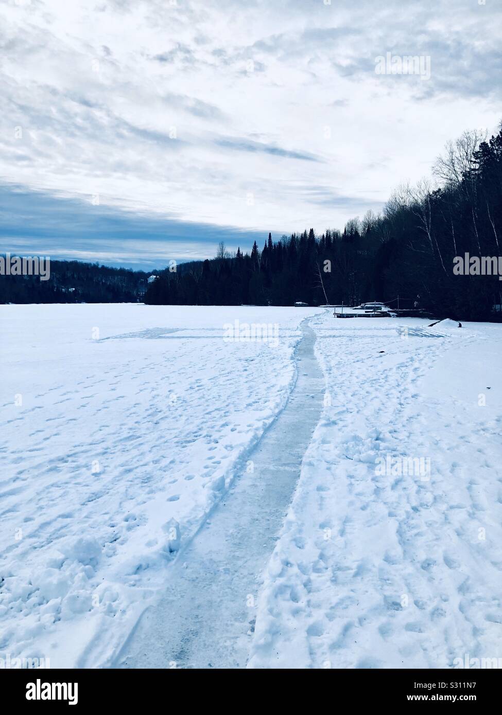 Chemin sur le lac en hiver. Paysage dans un jour nuageux dans Laurentides, Québec, Canada. - Image de stock capturée avec un smartphone