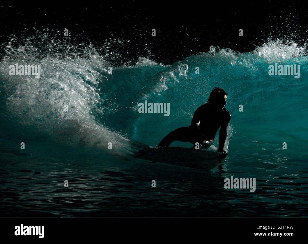 Un surfeur surf de nuit, illuminé par un éclair. Banque D'Images