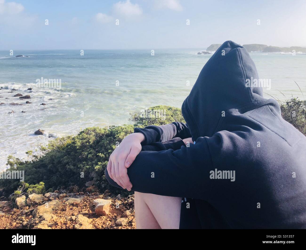 Teenage boy dans un hoody regarder la mer Banque D'Images