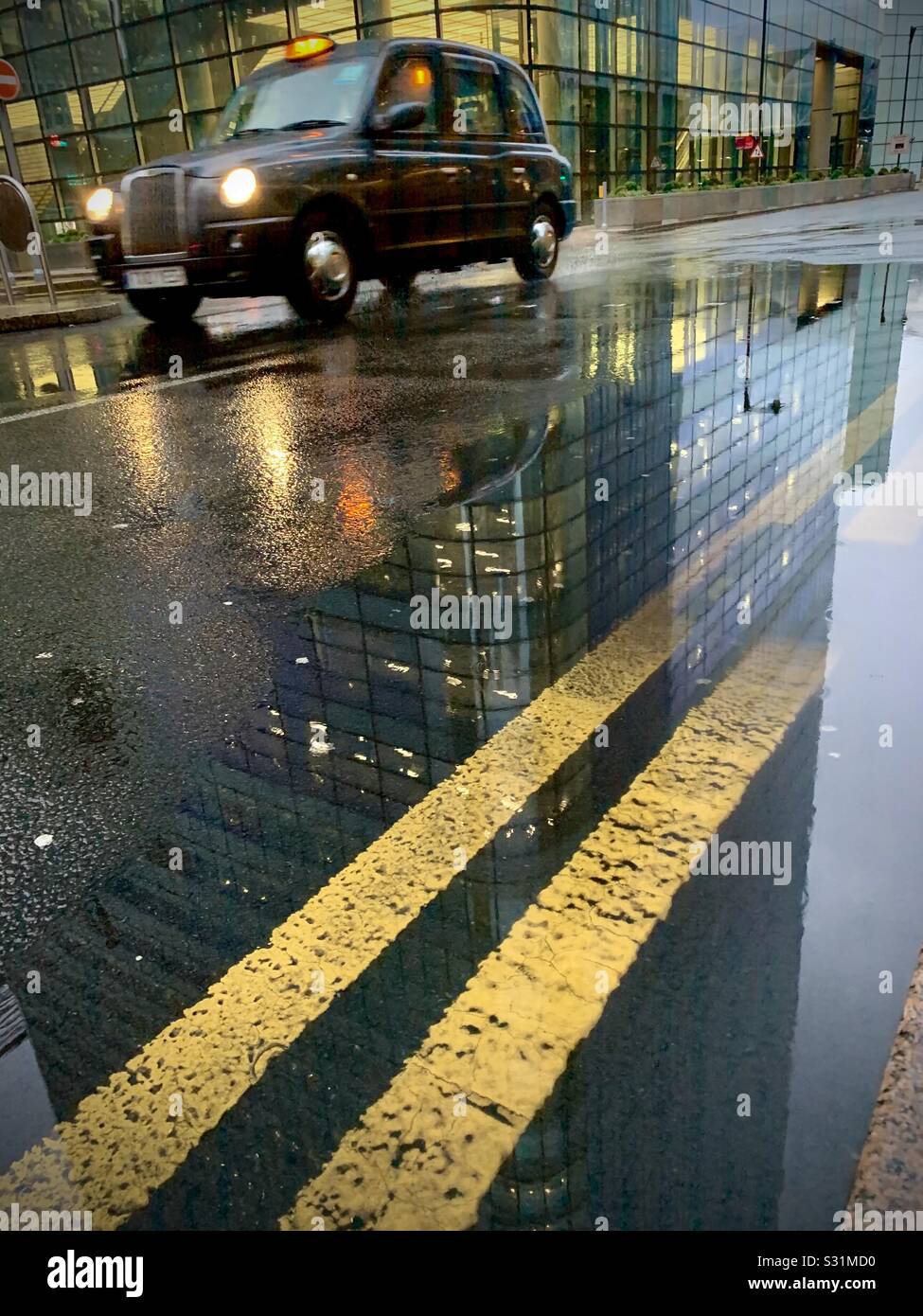 Cabine noire pour une journée de pluie à Canary Wharf avec deux lignes jaunes Banque D'Images