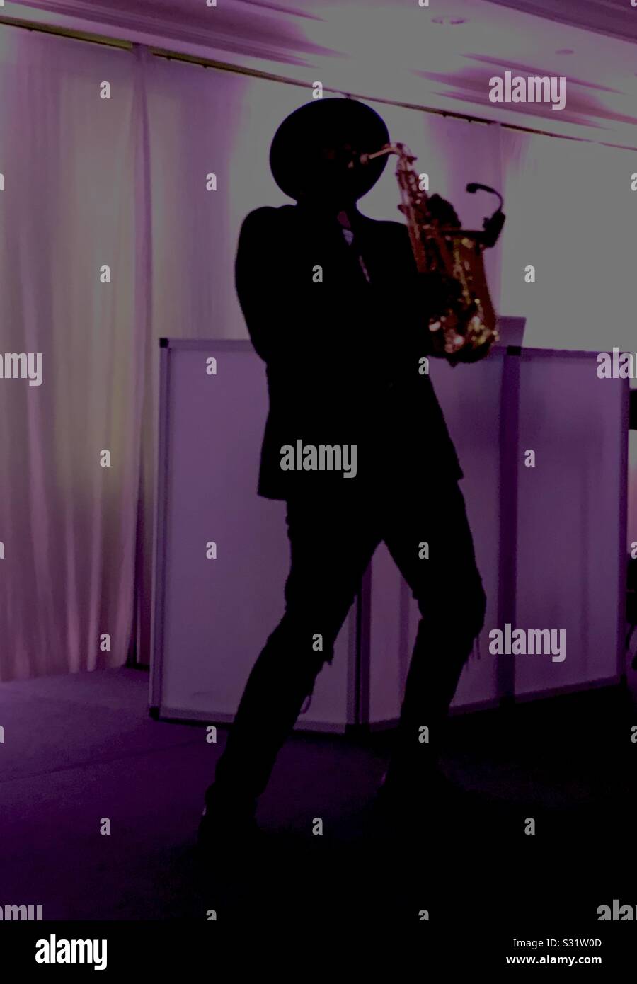 Un homme d'effectuer et de jouer le saxophone alto en silhouette. Banque D'Images