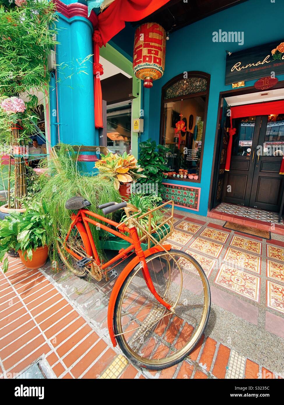 Location orange en face de passants colorés sur Joo Chiat Road dans la zone historique de Katong Singapore. Banque D'Images