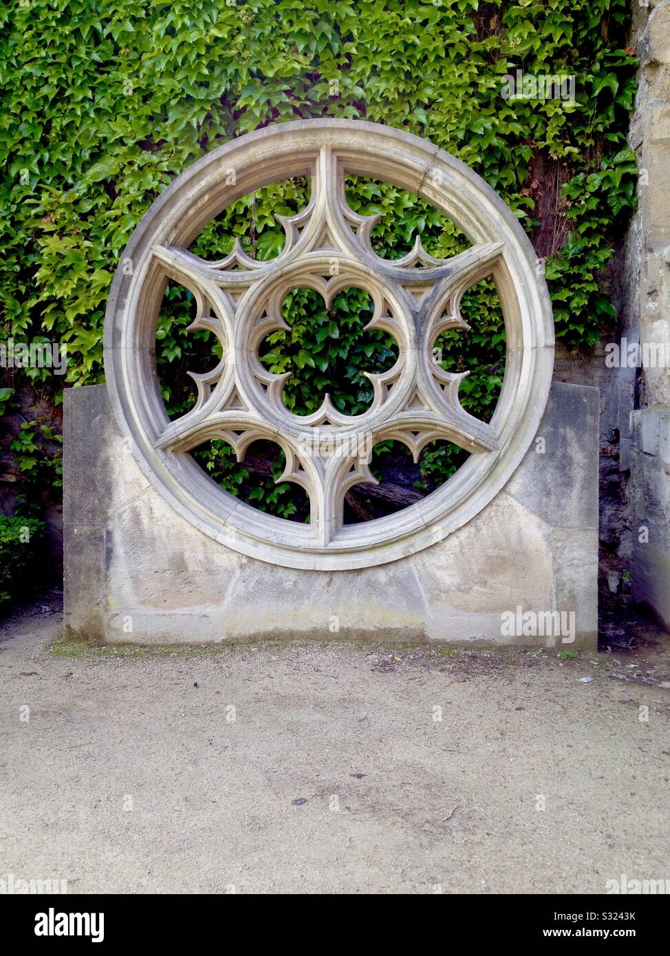 Structure architecturale décorative circulaire dans le Marais, Paris, France, avec un mur de lierre derrière lui. Banque D'Images